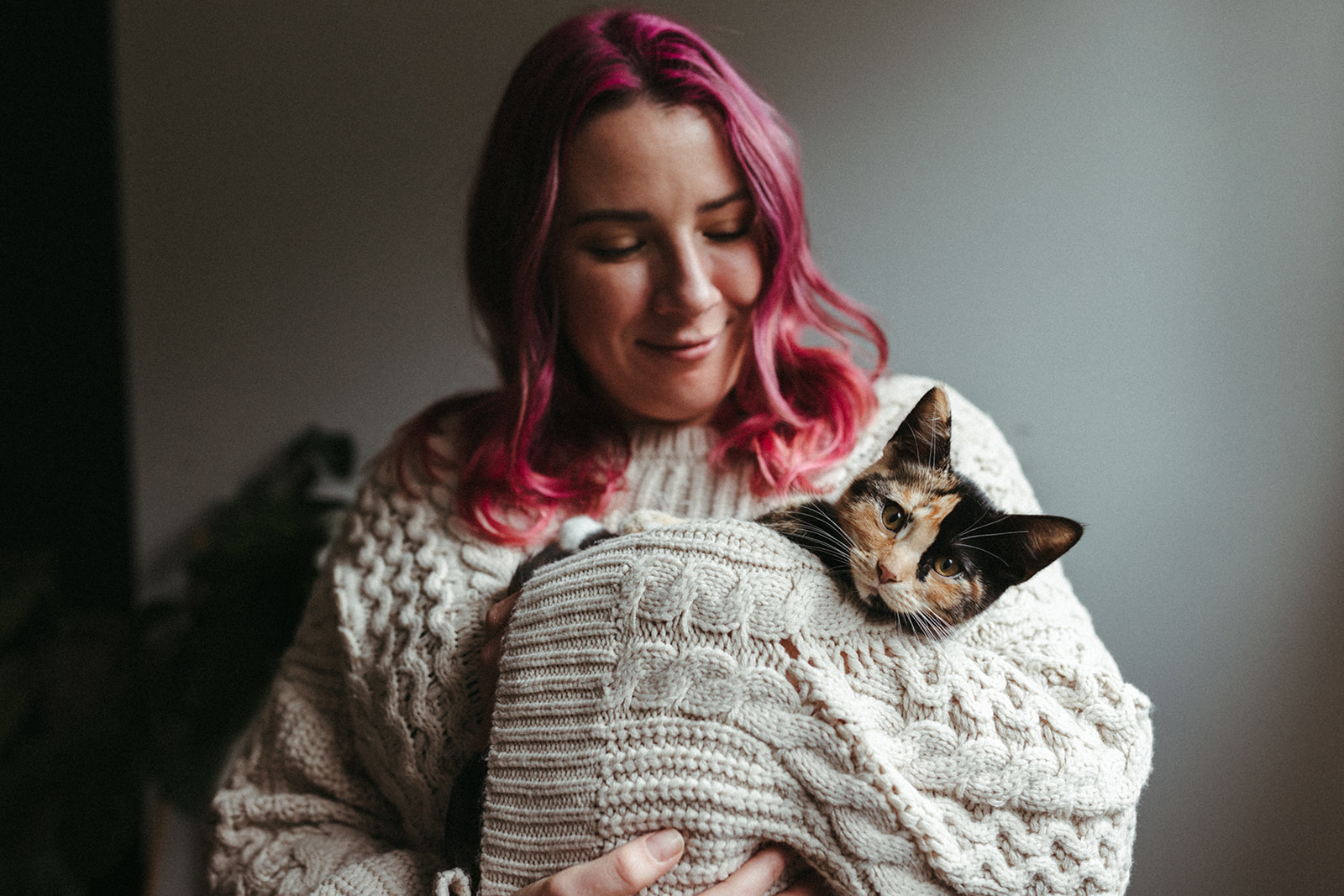 Girl with pink hair poses with her calico kitten 